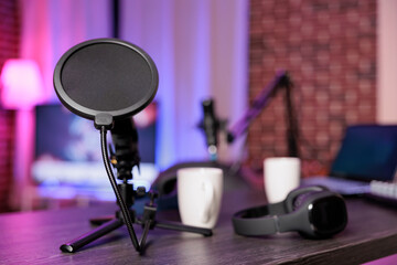 Close up shot of podcast microphone used to record internet show for online livestreaming channel. Streaming sound capturing and recording podcasting tool in empty living room with neon lights