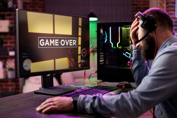 Gamer losing intense singleplayer spaceship arcade racing videogame, seeing game over screen on...