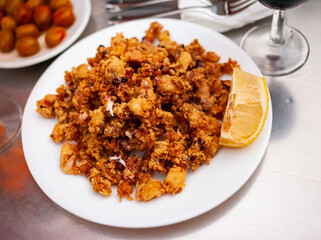 Traditional spanish dish Chipirones, battered fried baby squid served with lemon