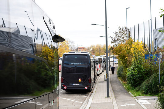Strasbourg, France - Nov 22, 2023: A dynamic shot capturing the reflections on a parked bus along Bd Pierre Pflimlin in Strasbourg, with a line of coaches in the background and pedestrians walking by.