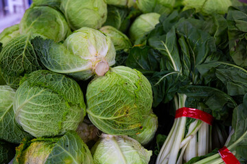 Fresh green leafy vegetables (cabbage, lettuce, chard) for sale on counter of local market