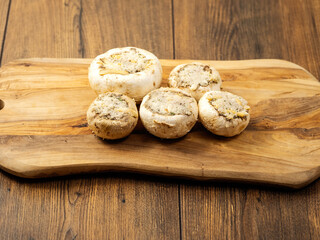 Stuffed mushrooms cups on a wooden board and table. High quality product with breadcrumbs, cheese...