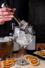 preparation of a shot of artisanal gin with lemon and orange slices and ice with the hand of a bartender