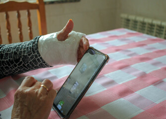 elderly woman with a cast wrist and a mobile phone