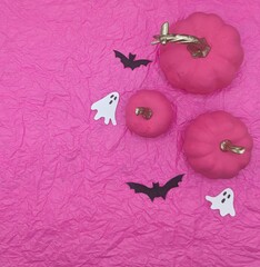 Pink pumkins, bats and ghosts on pink paper background.