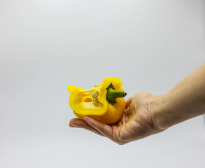 holding yellow cut paprika with white background