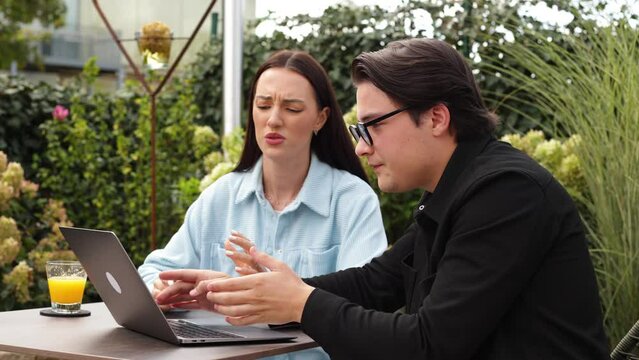 man makes excuses to girl for doing work on the computer in good weather in cafe