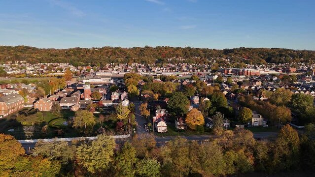 A profile laterally moving aerial establishing shot of a New England river town in the Autumn season. Pittsburgh suburbs.  	