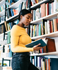 Interested ethnic student reading textbook in library