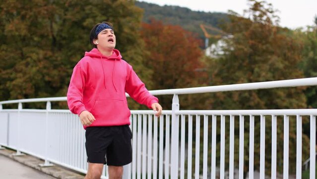 runner in colored clothes crosses bridge in morning.athlete is tired of running