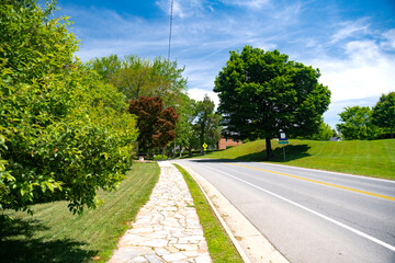 Fototapeta na wymiar asphalt road with a yellow dividing strip among trees. Blue cloudy sky.