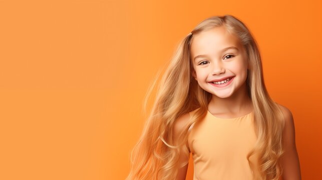 Portrait of little beautiful girl with long blond hair smiling, isolated on the orange background. Studio concept.