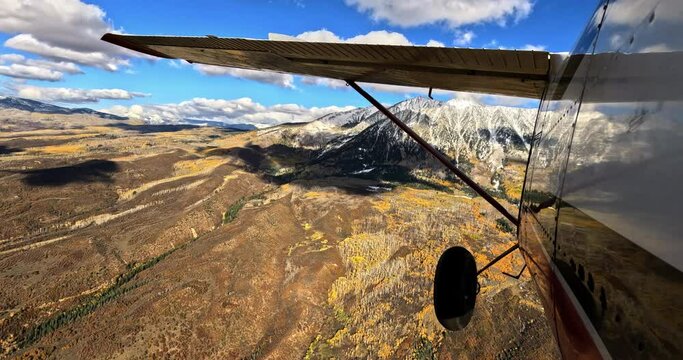 Airplane pov shot of wing flying through scenic mountains 
