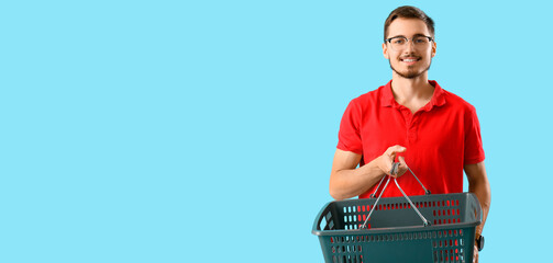Man holding empty shopping basket on light blue background with space for text