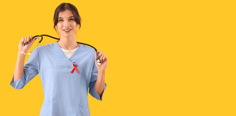 Female doctor with red ribbon on yellow background with space for text. World AIDS Day