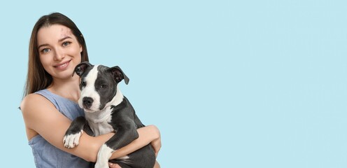 Young girl holding cute puppy on light blue background with space for text