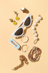 Stylish jewelry with sunglasses on beige background