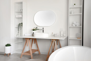 Fototapeta na wymiar Interior of light bathroom with white sink, bathtub and shelving units