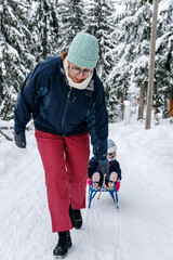 Little girl playing with mother on deep snow