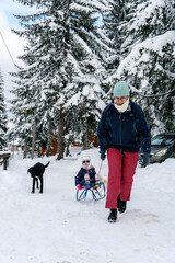 Little girl playing with mother on deep snow