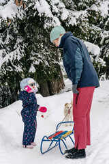 Little girl playing with mother on deep snow