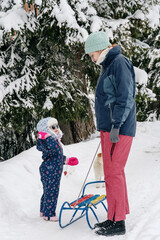 Little girl playing with mother on deep snow