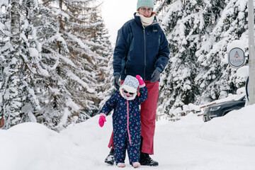 Little girl playing with mother on deep snow