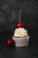 Tasty cherry cupcake on black background