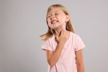 Suffering from allergy. Little girl scratching her neck on light gray background, space for text