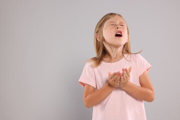 Suffering from allergy. Little girl sneezing on light gray background, space for text