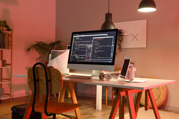 Programmer's workplace with devices in interior of dark office