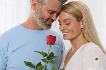 Happy affectionate couple with red rose at home. Romantic date