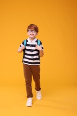 Naklejka premium Happy schoolboy in glasses on orange background