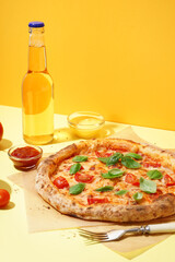Baking paper with tasty pizza Margarita and basil on yellow background