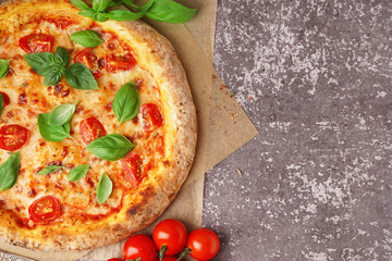 Baking paper with tasty pizza Margarita and basil on dark table