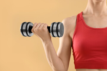 Young woman in sportswear doing exercises with dumbbells on beige background, closeup. Space for text