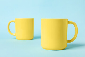 Two yellow ceramic mugs on light blue background