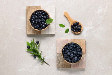 Tasty fresh bilberries and green leaves on light grey marble table, flat lay