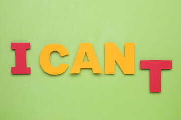 Motivation concept. Changing phrase from I Can't into I Can by removing letter T on light green background, flat lay