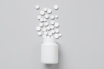 Fototapeta na wymiar Jar with scattered pills on grey background