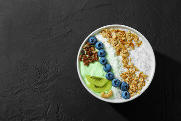 Tasty smoothie bowl with fresh kiwi fruit, blueberries and oatmeal on black table, top view. Space for text
