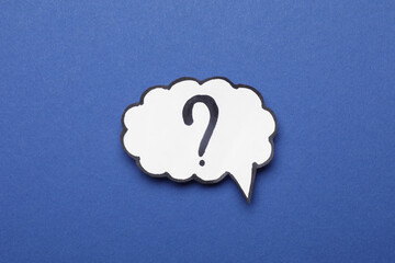 Paper speech bubble with question mark on blue background, top view