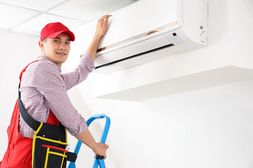 Fototapeta na wymiar Male technician fixing air conditioner in room