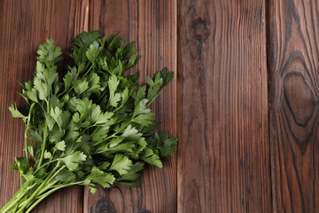 Bunch of fresh green parsley leaves on wooden table, top view. Space for text