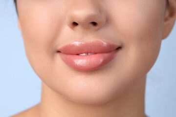 Obraz premium Young woman with beautiful lips on blue background, closeup