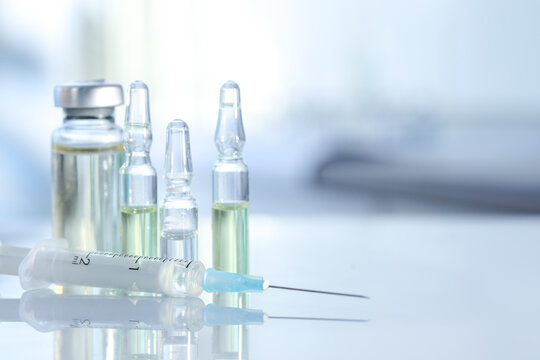 Glass vial, ampoules and syringe on white table, closeup. Space for text