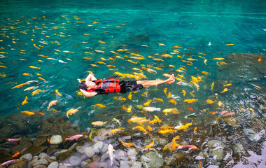 A tourist is swimming with fish in a clear lake of situ cipanten lakes Majalengka west java. 