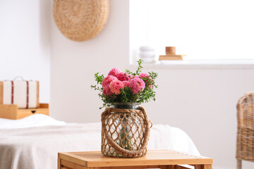 Wicker vase of beautiful pink dahlias on coffee table in bedroom