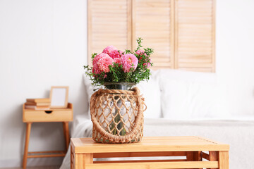 Fototapeta na wymiar Wicker vase of beautiful pink dahlias on coffee table in bedroom