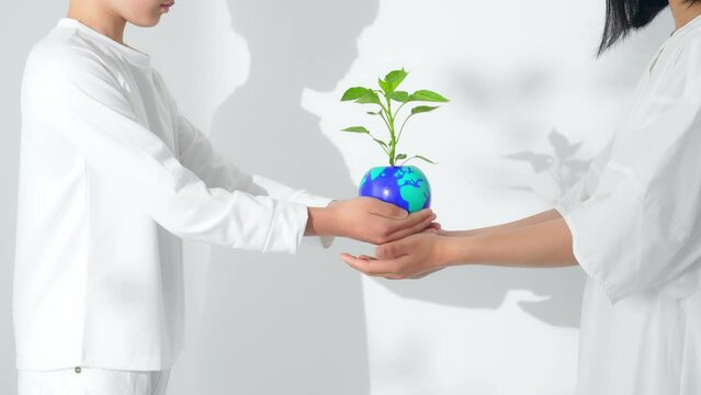 地球の描かれた植木鉢を受け渡す子供達　環境保護イメージ